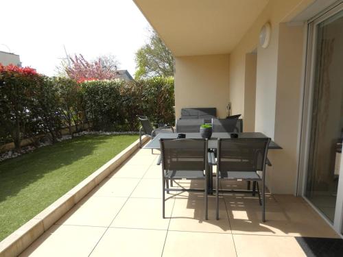 d'une terrasse avec des chaises et une table munie d'un ordinateur portable. dans l'établissement Quiet Garden - 10 minutes to Geneva, à Ornex