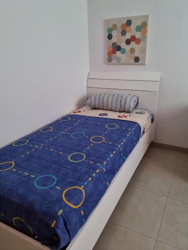 Una cama en una habitación con una manta azul encima. en Southern Court Apartment, en Il-Ħamrija