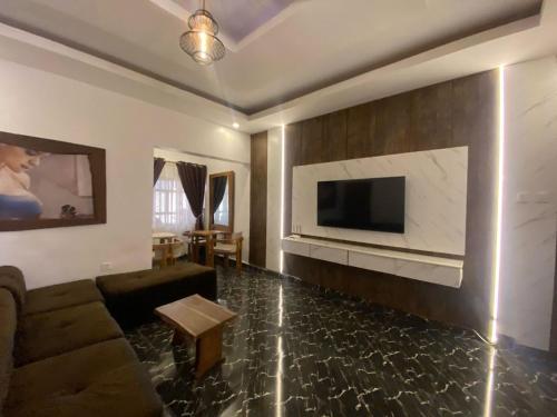 a living room with a couch and a tv on a wall at Presken Hotel and Resorts MOJIDI in Ikeja