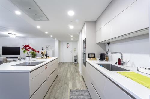 a kitchen with white counters and sinks and a tv at Imperatriz Madeira Apartment in Funchal