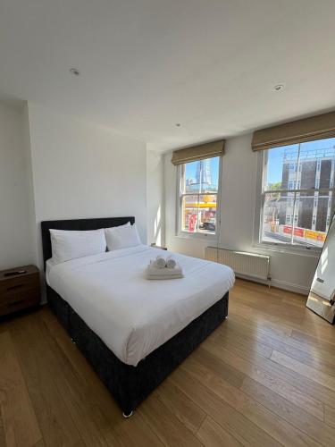 a bedroom with a large white bed with two windows at Cosy Townhouse In Central London in London