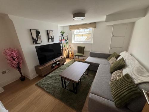 a living room with a couch and a flat screen tv at Cosy Townhouse In Central London in London