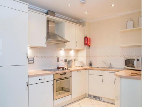 a kitchen with white cabinets and a microwave at Oakdale at Centrium in Woking