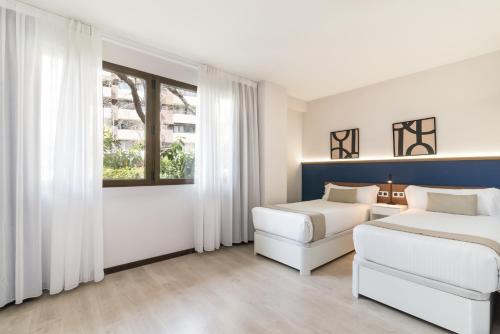 two beds and a couch in a room with a window at Roisa Hostal Boutique in Madrid