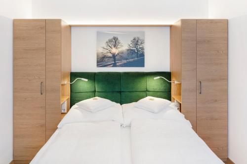 a bedroom with two beds and a green headboard at Gasthof zum Goldenen Hirschen in Ybbsitz