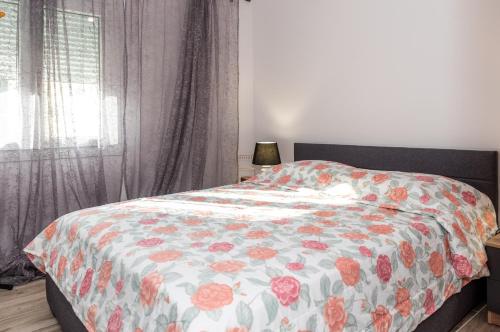 a bedroom with a bed with a floral comforter and a window at Nina's Apartments in Kómi