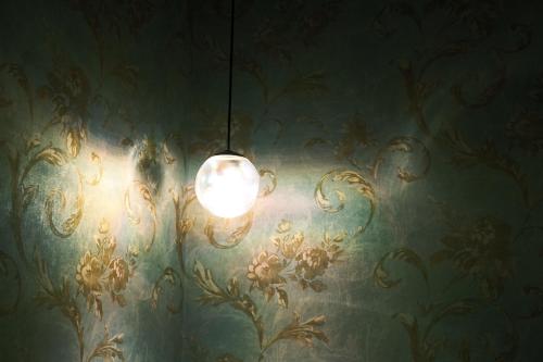 a light hanging from a wall with a floral wallpaper at ゲストハウス桜月荘 in Kagoshima