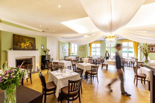 a man walking through the dining room of a restaurant at Café Wildau Hotel & Restaurant am Werbellinsee in Schorfheide