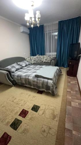1 dormitorio con cama, TV y cortinas azules en House, en Aktobe