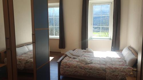 a small bedroom with a bed and two windows at Locanda EL TORO in Arnoldstein