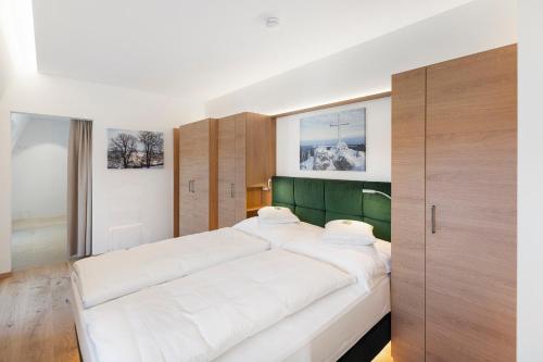 a bedroom with a large white bed with a green headboard at Gasthof zum Goldenen Hirschen in Ybbsitz
