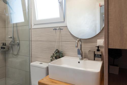 a bathroom with a sink and a mirror and a toilet at Nina's Apartments in Kómi