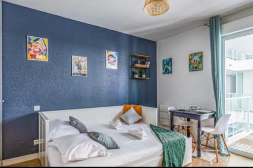 une chambre avec un lit blanc avec un mur bleu dans l'établissement Studio with balcony in the heart of La Rochelle, à La Rochelle