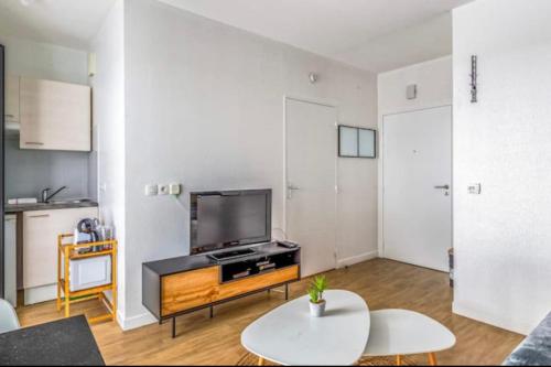 un salon avec une télévision et une table dans l'établissement Studio with balcony in the heart of La Rochelle, à La Rochelle