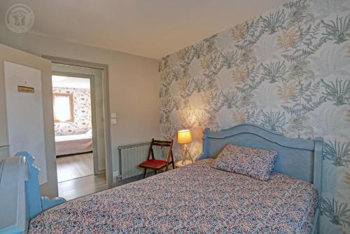 a bedroom with a blue bed and floral wallpaper at Au plein soleil in Chazelles-sur-Lyon