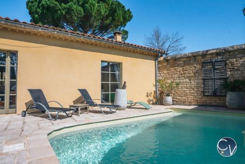 une piscine avec deux chaises et une maison dans l'établissement Maison en pierre avec piscine à Barjac, 16 personnes, à Barjac