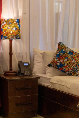 a lamp on a table next to a couch with a pillow at Trisan Resident Hotel in Nairobi