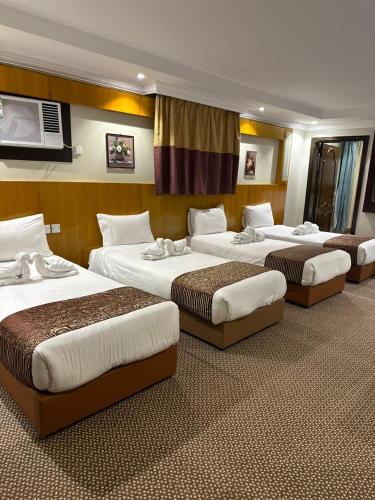 a group of four beds in a hotel room at فندق المغاربي للشقق الفندقية in Al Madinah