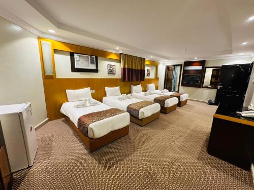 a hotel room with three beds and a television at فندق المغاربي للشقق الفندقية in Al Madinah