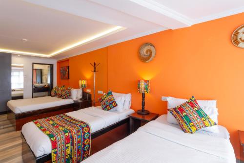 two beds in a room with orange walls at Trisan Resident Hotel in Nairobi