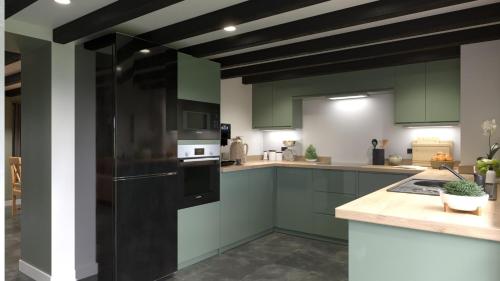 a kitchen with green cabinets and a black refrigerator at Talland Cottage 4 bedroom with Hot Tub in Looe