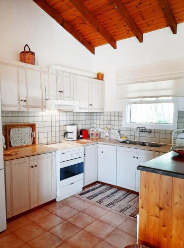 a kitchen with white cabinets and a sink at Agrilis Cottage near the beach in Ágrilos