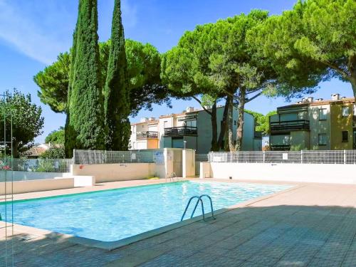 une piscine avec des arbres et un bâtiment dans l'établissement Studio Cabine - Piscine & Parking, au Grau-dʼAgde