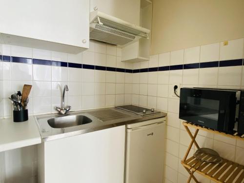 une petite cuisine avec un évier et un micro-ondes dans l'établissement le ROUERGAT, à Rodez