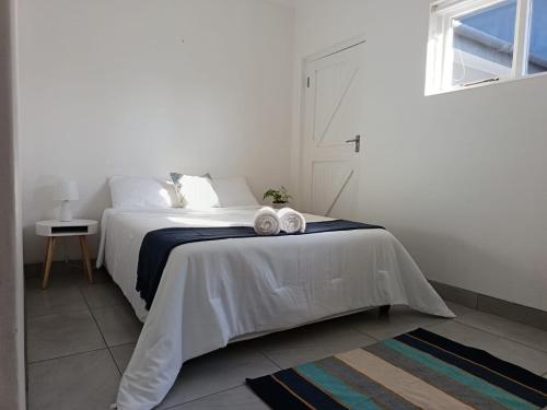 a white bedroom with a bed with towels on it at Hartsepunt in Mossel Bay
