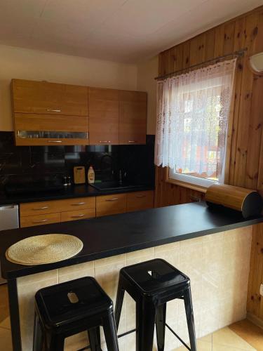 a kitchen with a black counter and two stools at Leśny Zakątek - Domek nad samym jeziorem in Gołdap