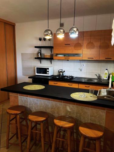 a kitchen with a counter with four stools in it at Leśny Zakątek - Domek nad samym jeziorem in Gołdap