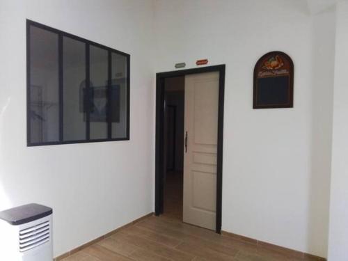 un couloir avec une porte et une horloge sur un mur dans l'établissement Domaine des Guilardières, à Marigné-Laillé