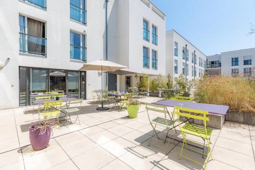 a patio with tables and chairs in front of a building at Appart'City Classic Chalon sur Saone in Chalon-sur-Saône