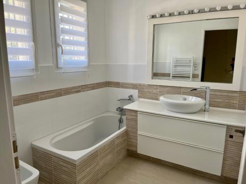 une salle de bain avec une baignoire, un lavabo et un miroir dans l'établissement Villa avec prestations de qualité, à Draguignan