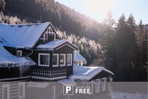 a house with snow on the roof of it at CHATA LESOVNA in Pec pod Sněžkou