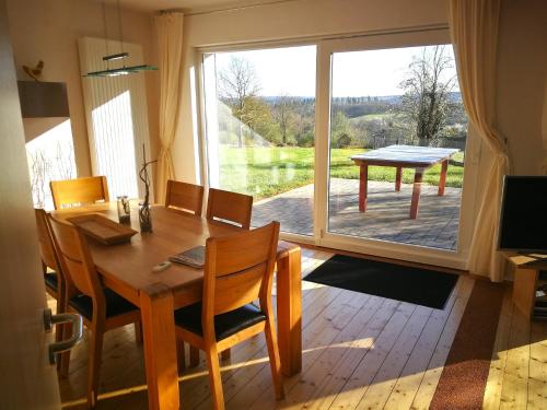 a dining room with a table and a large window at Das Burgberghaus Apartment Auwald in Hürtgenwald