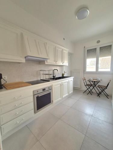 - une cuisine avec des placards blancs, un évier et une table dans l'établissement Appartement Le Saint Pierre, à Arles