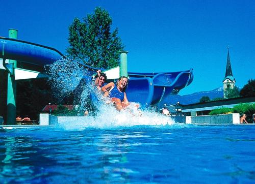 two people on a water slide in the water at Gästehaus-Pension Bendler in Kirchdorf in Tirol