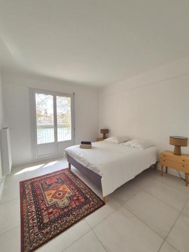 - une chambre avec un lit, un tapis et une fenêtre dans l'établissement Appartement Le Saint Pierre, à Arles