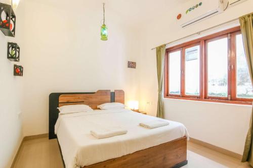a bedroom with a bed with white sheets and a window at Rainforest - Casa Azure 5 Min walk to the beach in Calangute
