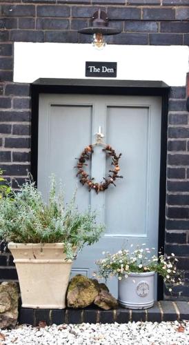 a blue door with two potted plants in front of it at 'The Den' - Malvern - A King Size or Twin Beds plus a Sofa Bed in Great Malvern