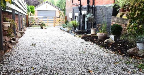 a gravel driveway with potted plants on the side of a house at 'The Den' - Malvern - A King Size or Twin Beds plus a Sofa Bed in Great Malvern