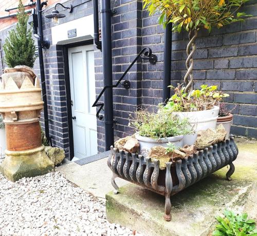 a bench with potted plants on it in front of a door at 'The Den' - Malvern - A King Size or Twin Beds plus a Sofa Bed in Great Malvern
