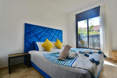 马拉喀什Oasis de l'Atlas by Golf Resort的一间卧室配有一张带蓝色床头板的床和窗户