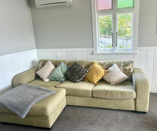a couch with pillows sitting in a room with a window at Character Home in Prime Location in Whangarei