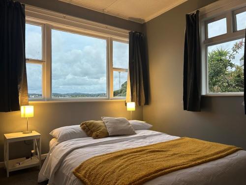 a bedroom with a bed and two windows at Character Home in Prime Location in Whangarei