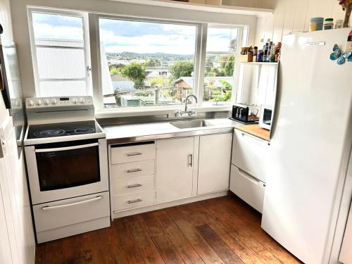 a kitchen with white appliances and a large window at Character Home in Prime Location in Whangarei