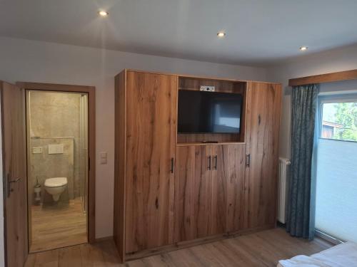 a room with a large wooden cabinet with a flat screen tv at Pension Zillnhäusl in Schönau am Königssee
