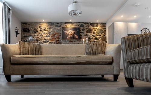 a couch in a living room with a stone wall at Castle Street Apartments - Luxury Scalpsie Apartment in Rothesay
