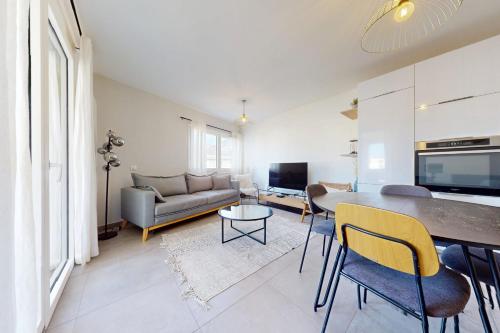 un salon avec un canapé et une table avec des chaises dans l'établissement Le Concert - Confortable 3 pièces de 60 m proche lac et Vieille Ville, à Annecy